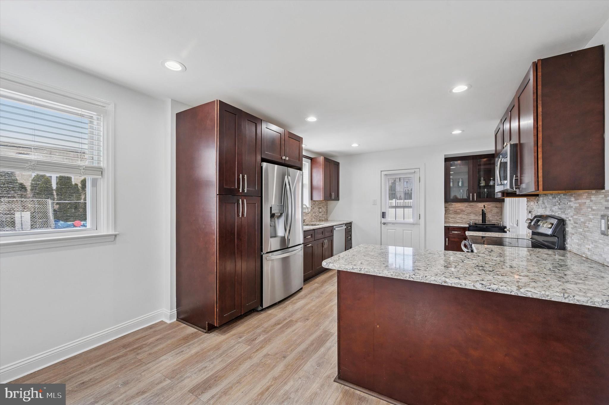 24 Upland Road Havertown, PA 19083 - Photo 12 of 28 a kitchen with stainless steel appliances granite countertop a refrigerator a stove and a sink with wooden floor