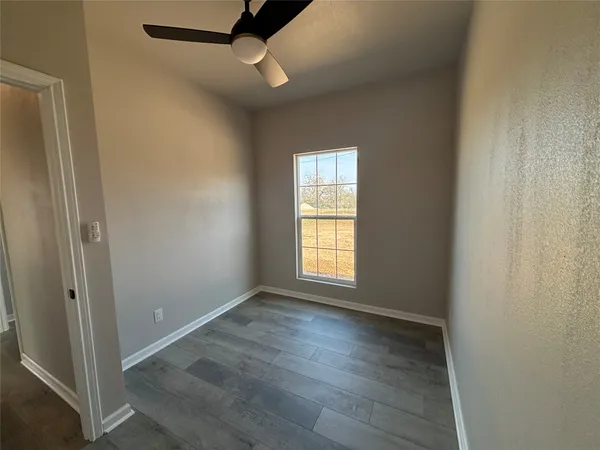 a view of an empty room with a window and wooden floor