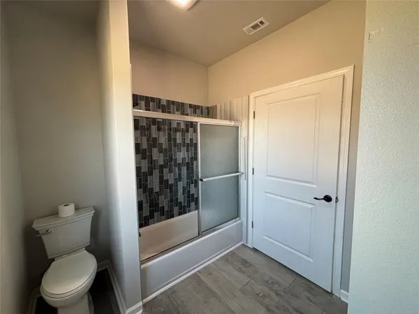 an empty room with wooden floor cabinet and windows