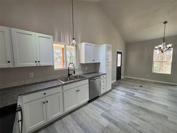 a kitchen with granite countertop white cabinets white stainless steel appliances with a sink and dishwasher