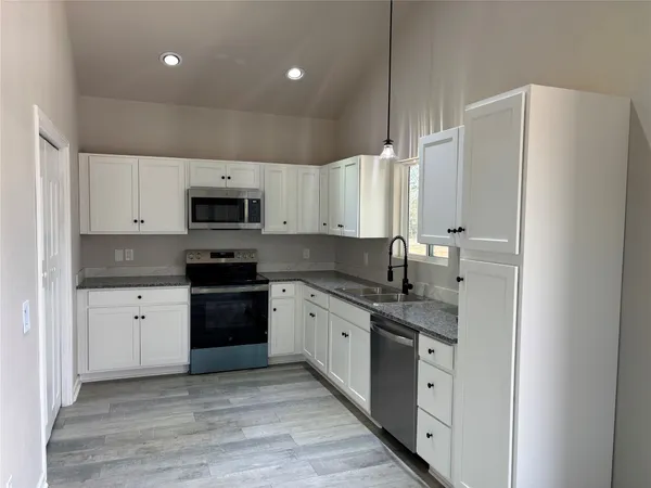 a large kitchen with stainless steel appliances granite countertop a stove sink and cabinets
