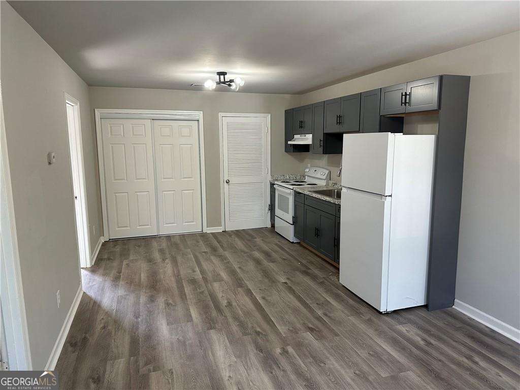 432 4th Avenue Dalton, GA 30721 - Photo 4 of 25 a view of a kitchen with a refrigerator a stove top oven and cabinets