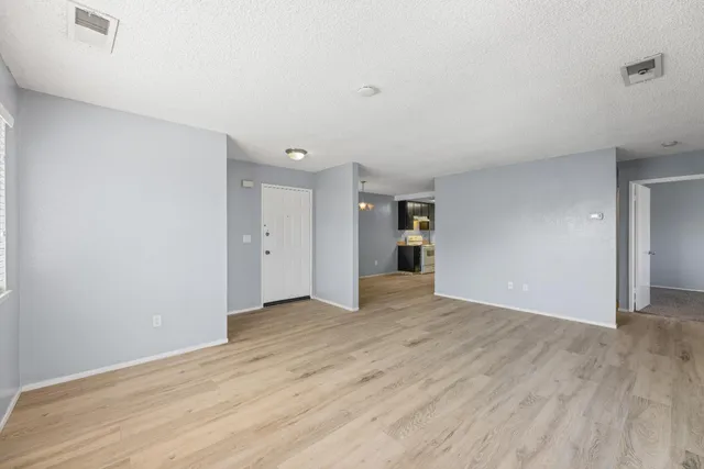 a view of an empty room with wooden floor and closet