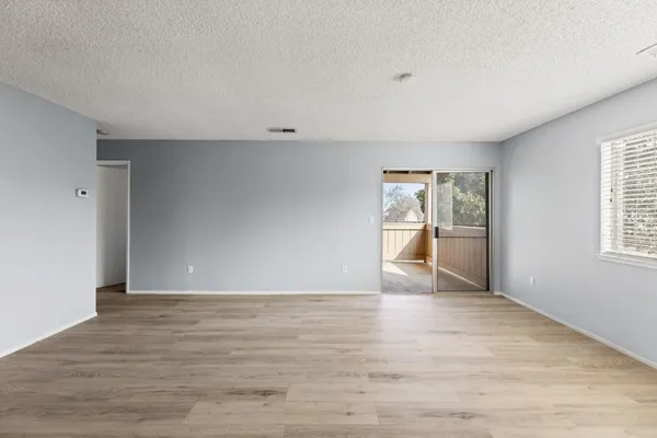 a view of an empty room with a window and wooden floor