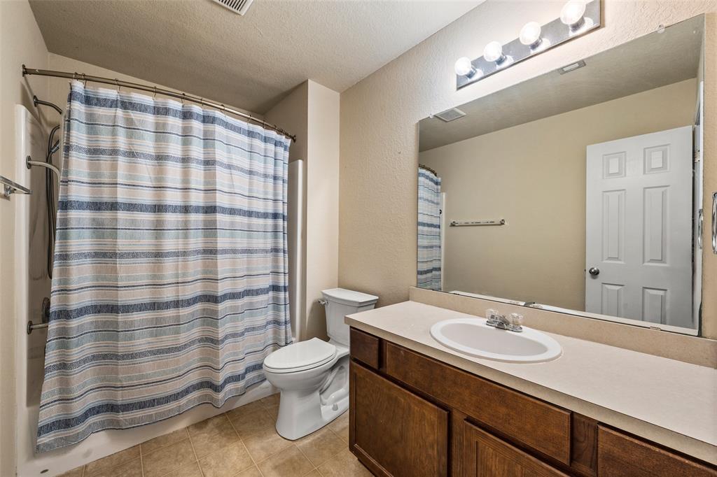 10512 Granada Drive Waco, TX 76708 - Photo 13 of 22 a bathroom with a sink a toilet a mirror and shower curtain