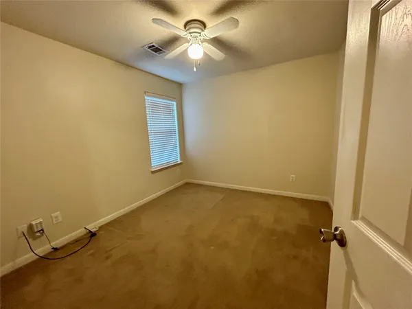 an empty room with a chandelier fan and a window