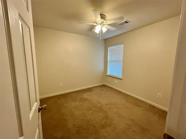 an empty room with a chandelier fan and a window