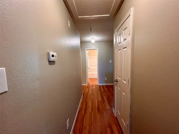 a view of a hallway with wooden floor and a bathroom