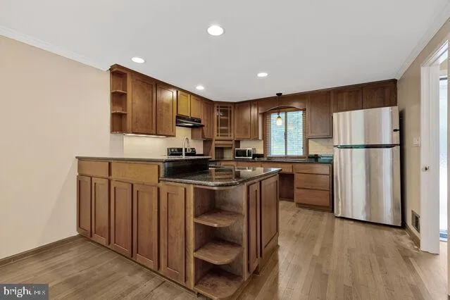 a kitchen with a refrigerator a stove top oven a sink and cabinets