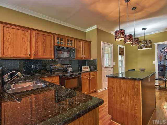 8008 Mill Bluff Court Raleigh, NC 27616 - Photo 6 of 25 a kitchen with stainless steel appliances granite countertop a sink a stove and a wooden cabinets