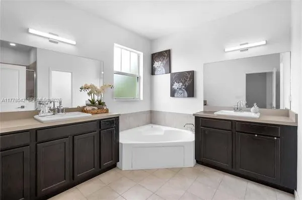 a bathroom with a tub a sink double vanity and mirror