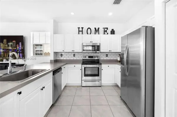 a kitchen with stainless steel appliances granite countertop a stove a sink and a refrigerator