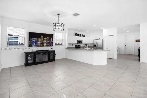 a large white kitchen with a stove a sink dishwasher and a refrigerator with kitchen island