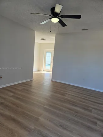 a view of an empty room with window and wooden floor