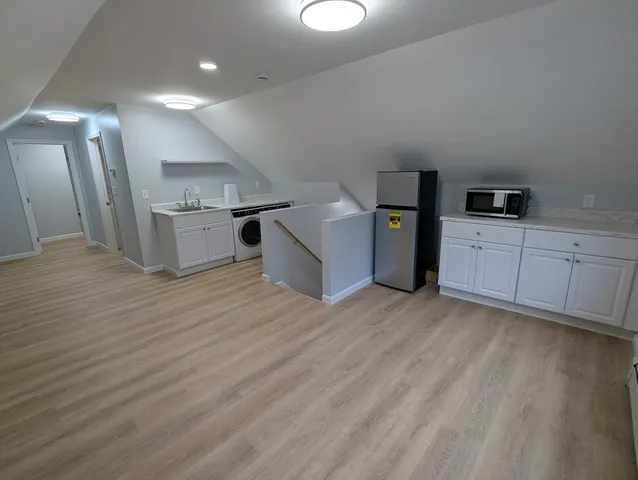 a kitchen with a sink wooden floor and black appliances