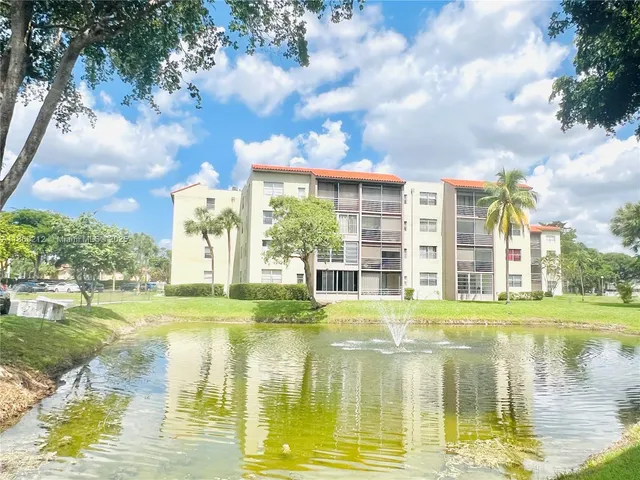 a view of a lake with a big yard and large trees