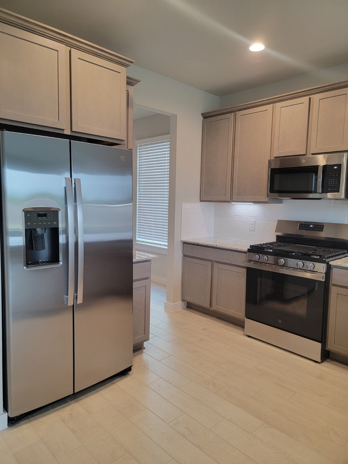 3130 Boulder Ridge Drive Rosenberg, TX 77471 - Photo 9 of 32 a kitchen with stainless steel appliances kitchen island granite countertop a stove a microwave and a refrigerator
