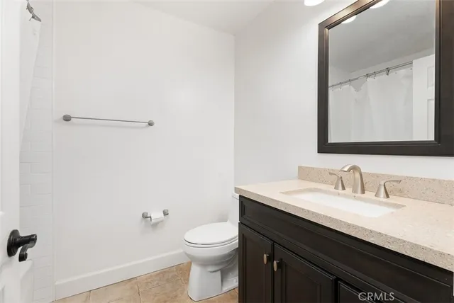 a bathroom with a granite countertop sink a toilet and a mirror
