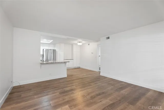 a view of kitchen and empty room with wooden floor