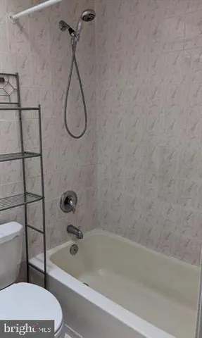 a bathroom with a granite countertop toilet and a bath tub