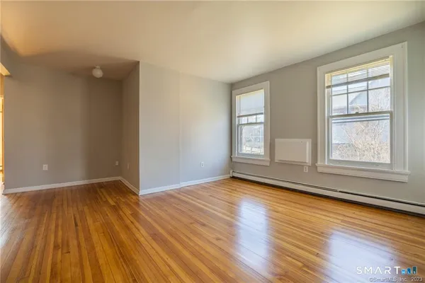 an empty room with wooden floor and windows