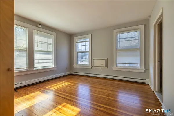 a view of an empty room with wooden floor and a window