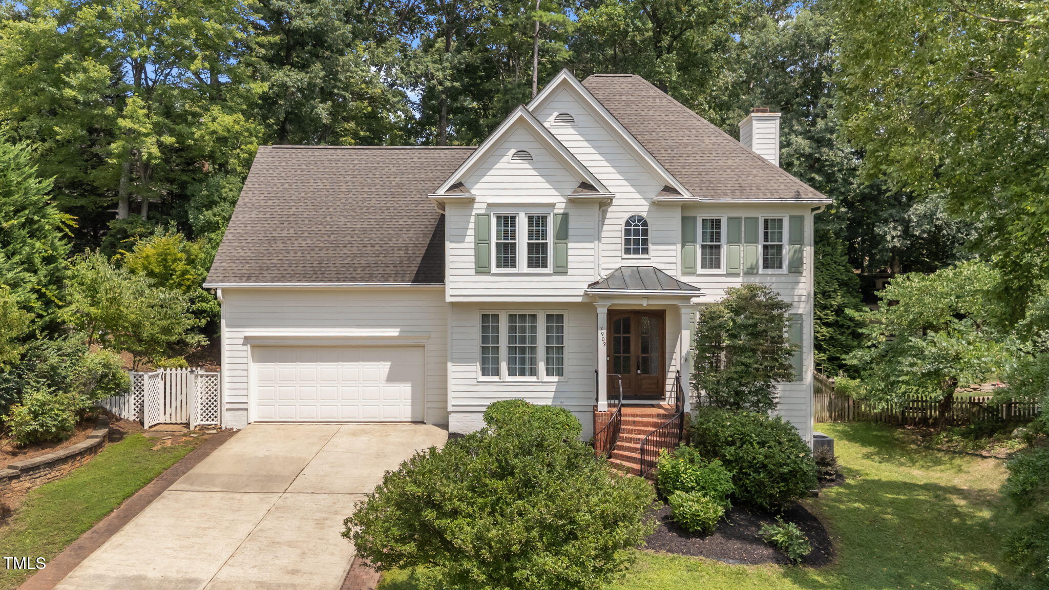 a aerial view of a house with a yard plants and large tree