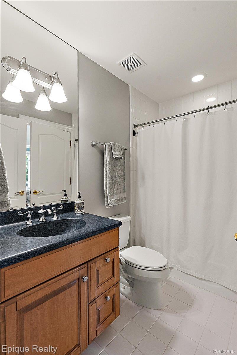7662 Devins Ridge Clarkston, MI 48348 - Photo 66 of 81 Bathroom featuring a wood-finish vanity with a dark countertop and integrated sink, a large wall mirror, a toilet, and a shower with a white curtain
