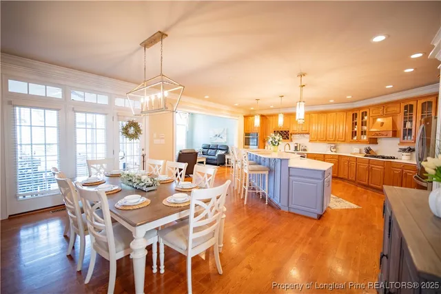 a dining room with wooden floor a chandelier a glass table and chairs