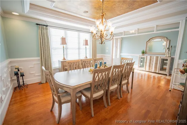 a dining room with furniture a chandelier and wooden floor