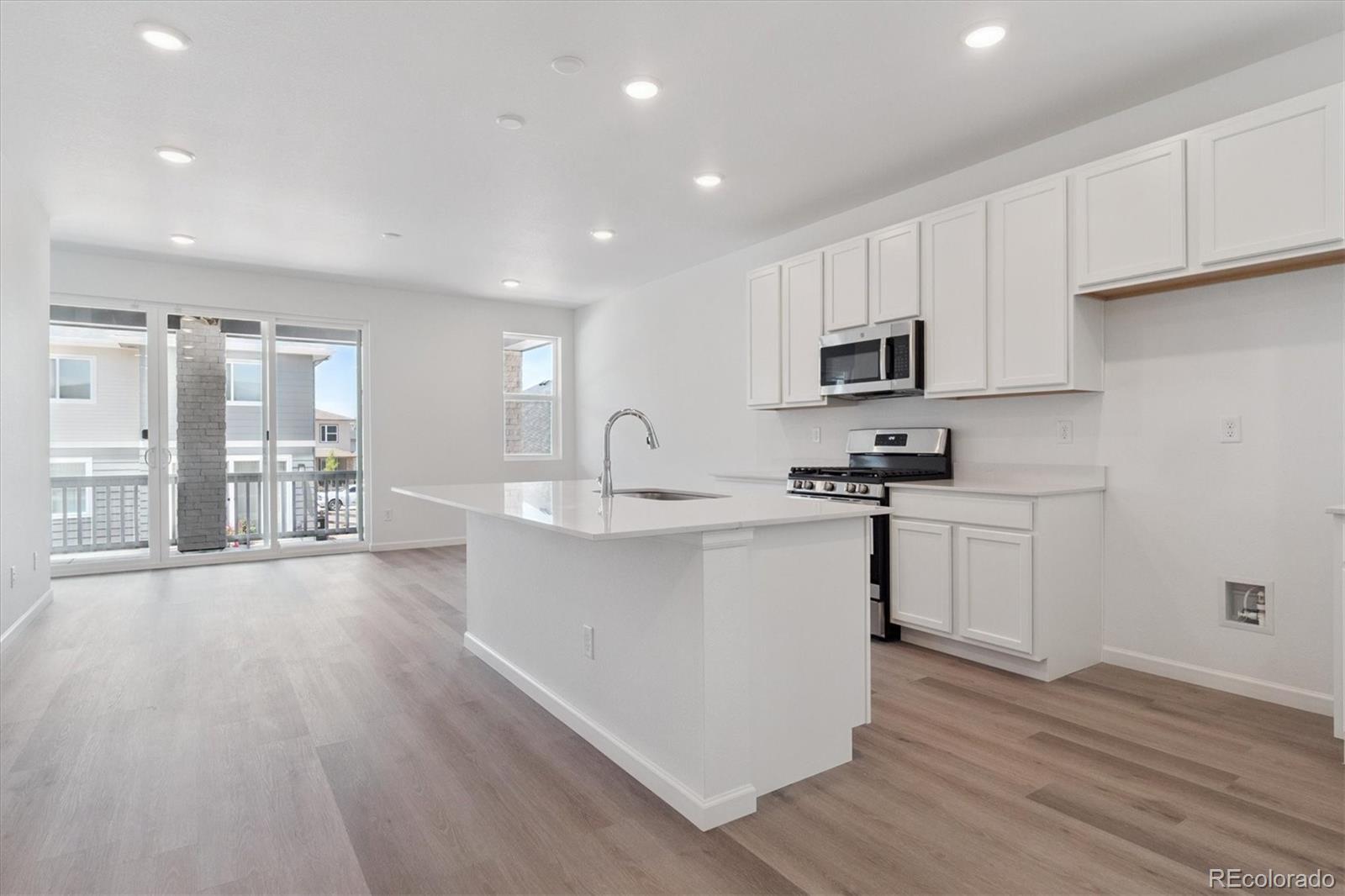 8317 Eagle River Street Littleton, CO 80125 - Photo 5 of 18 a kitchen with granite countertop a stove top oven a sink a counter space and cabinets