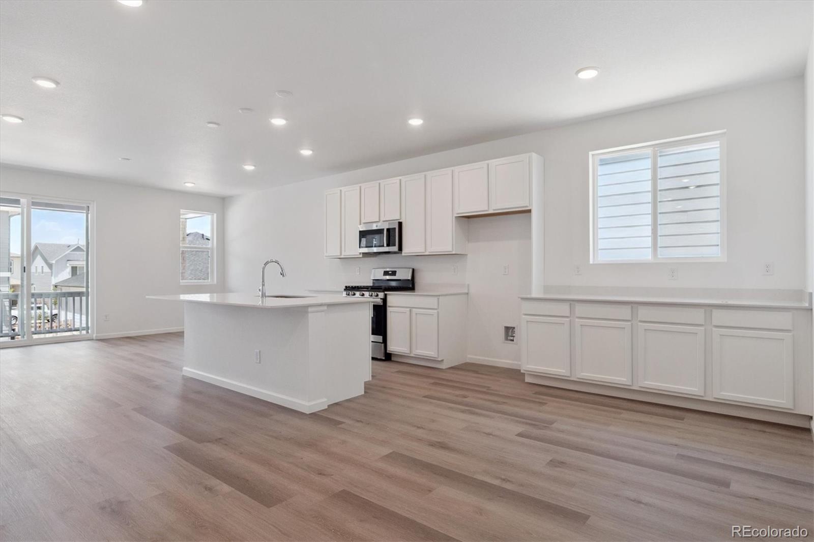 8317 Eagle River Street Littleton, CO 80125 - Photo 9 of 18 a large white kitchen with wooden floors and white walls