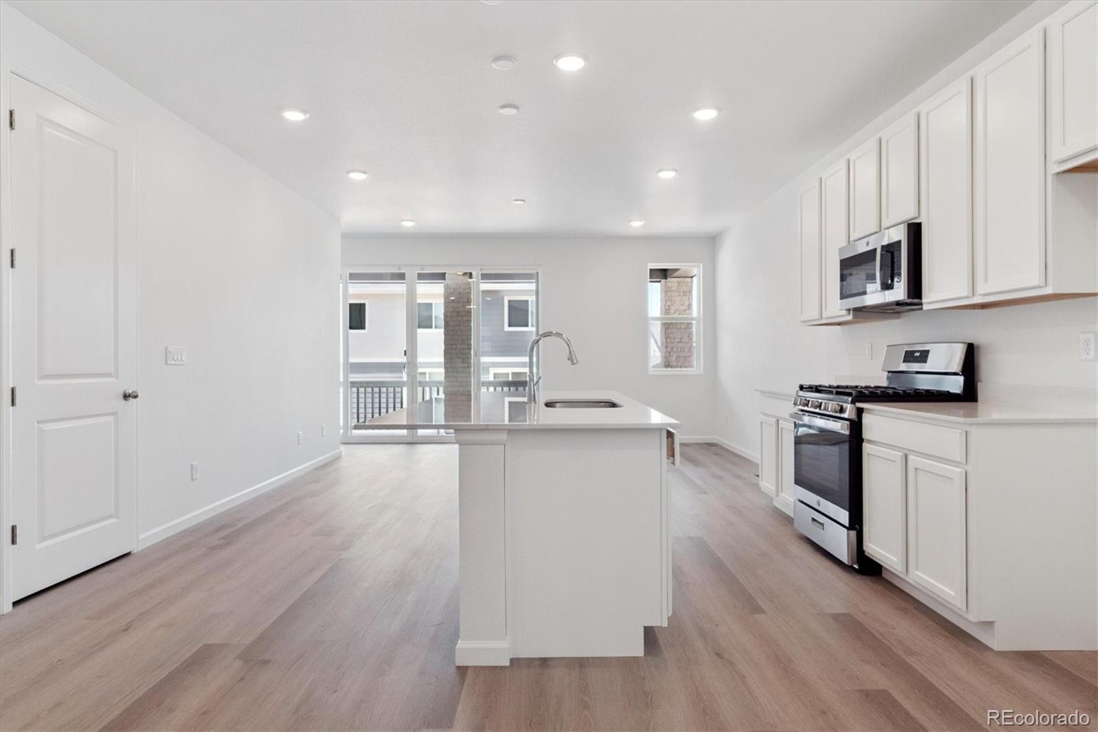 8317 Eagle River Street Littleton, CO 80125 - Photo 10 of 18 a large kitchen with stainless steel appliances granite countertop a lot of counter space and wooden floor