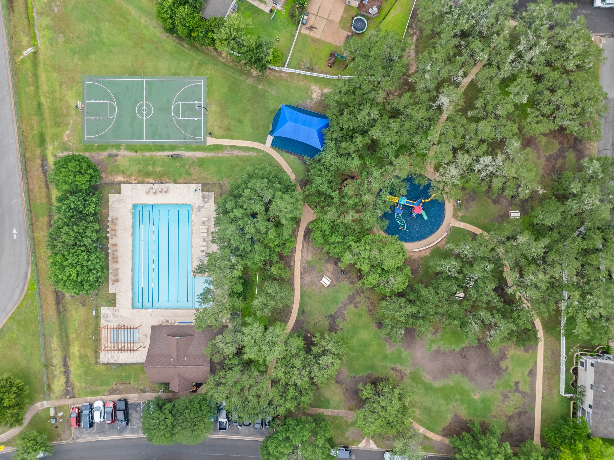 360 Sampson Kyle, TX 78640 - Photo 31 of 36 Outdoor recreation area featuring a multi-lane swimming pool, an outdoor basketball court, a shaded playground, and walking paths through mature trees