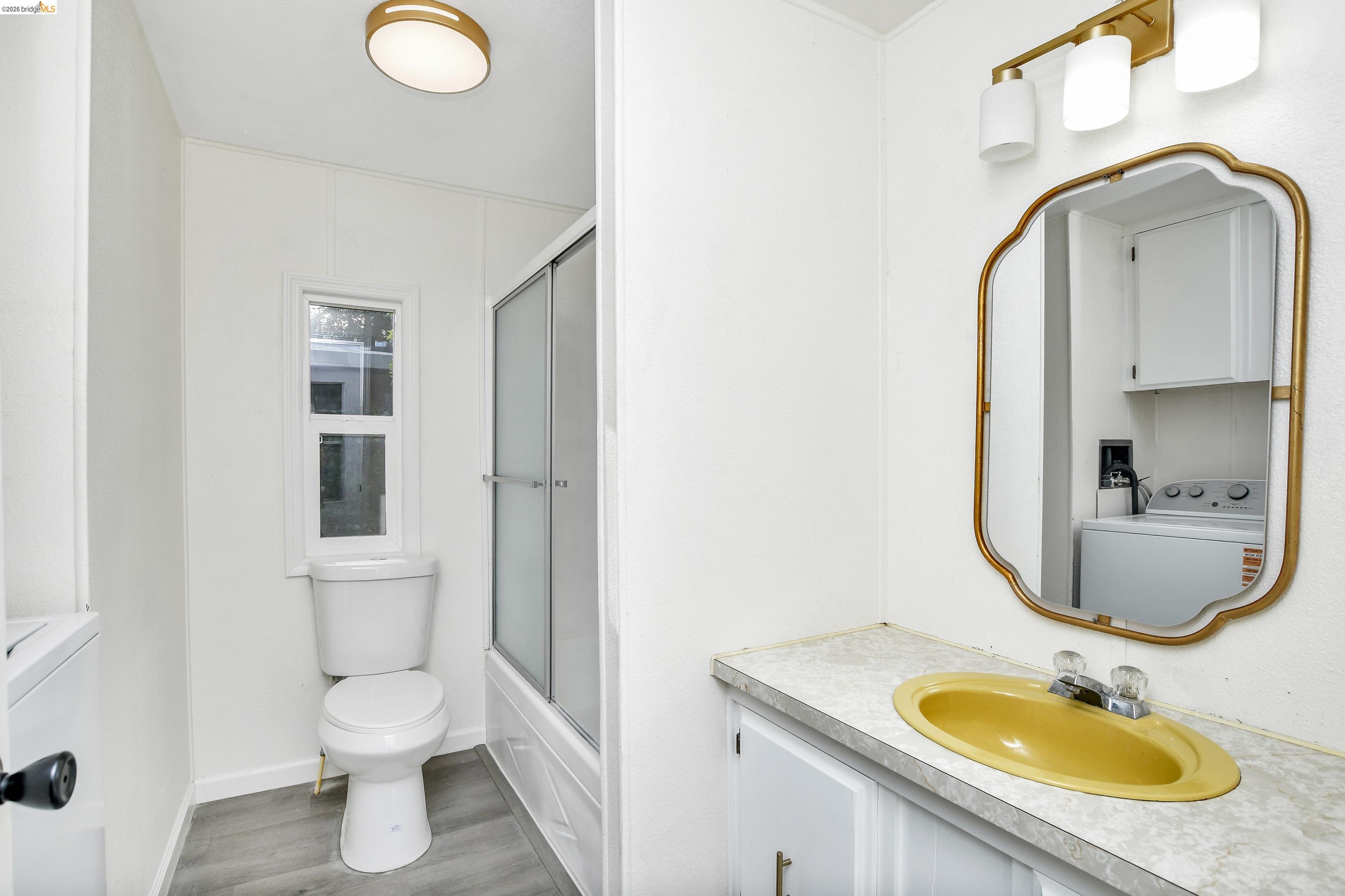 14 Del Rio Pittsburg, CA 94565 - Photo 10 of 25 Full hall bath featuring vanity, washer/dryer, shower-over-tub with glass door, and updated laminate floors