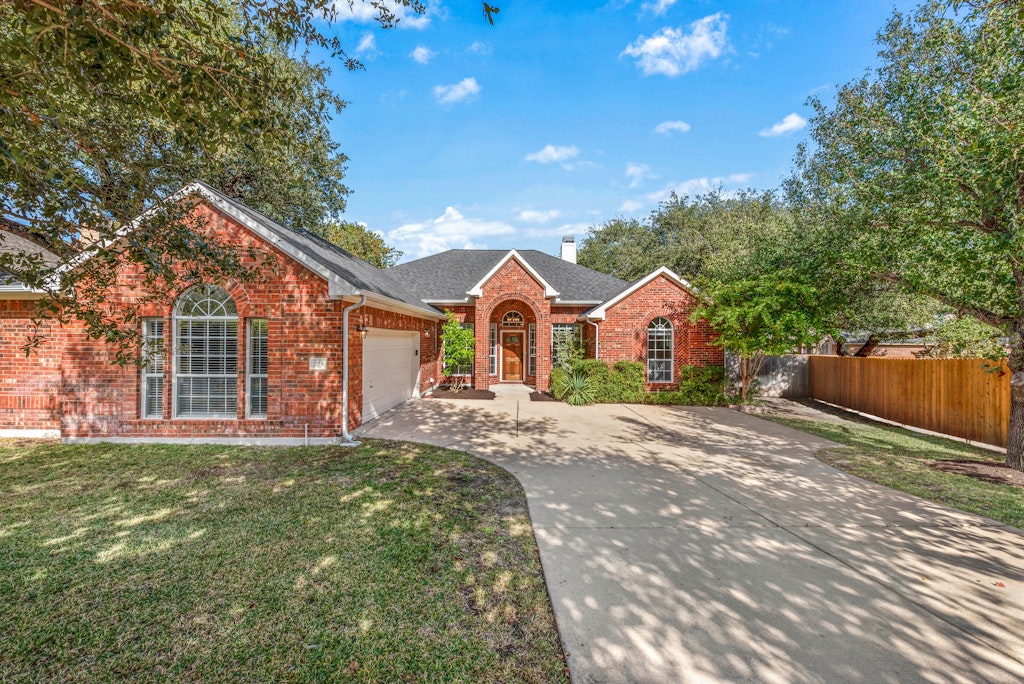 Single story home featuring driveway, a garage, and brick siding