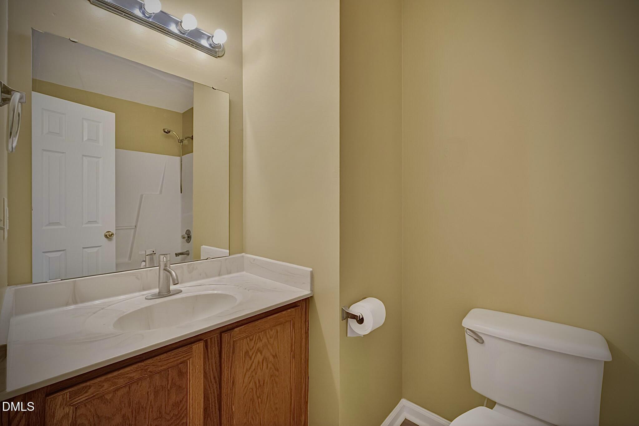 5415 Gunnette Drive Raleigh, NC 27610 - Photo 15 of 37 a bathroom with a granite countertop sink a toilet and a mirror