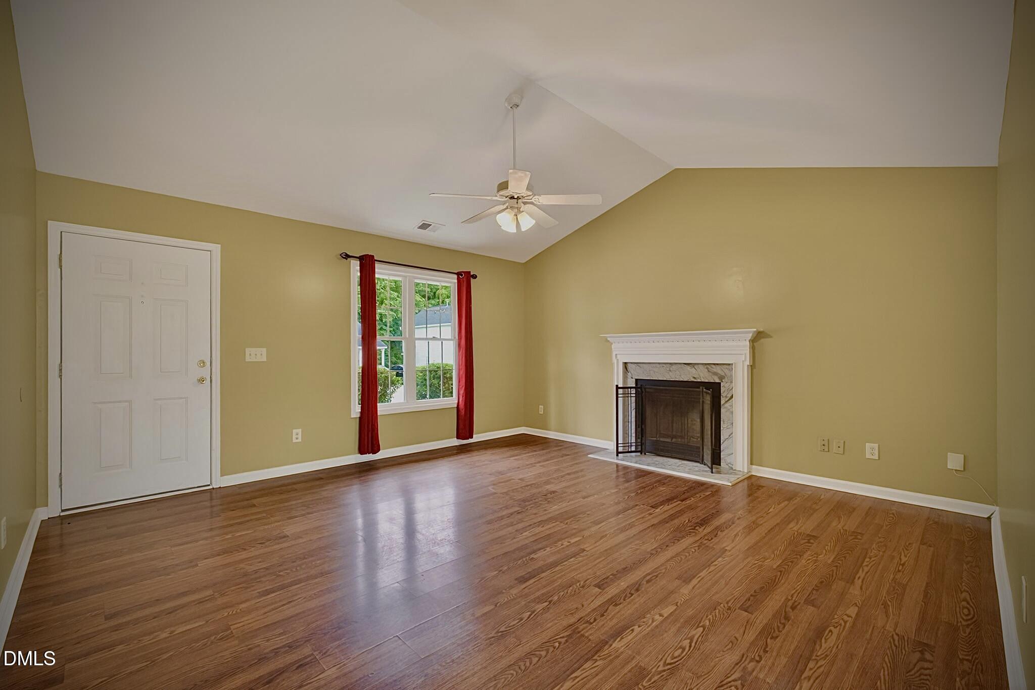 5415 Gunnette Drive Raleigh, NC 27610 - Photo 17 of 37 a view of an empty room with wooden floor fireplace and a window