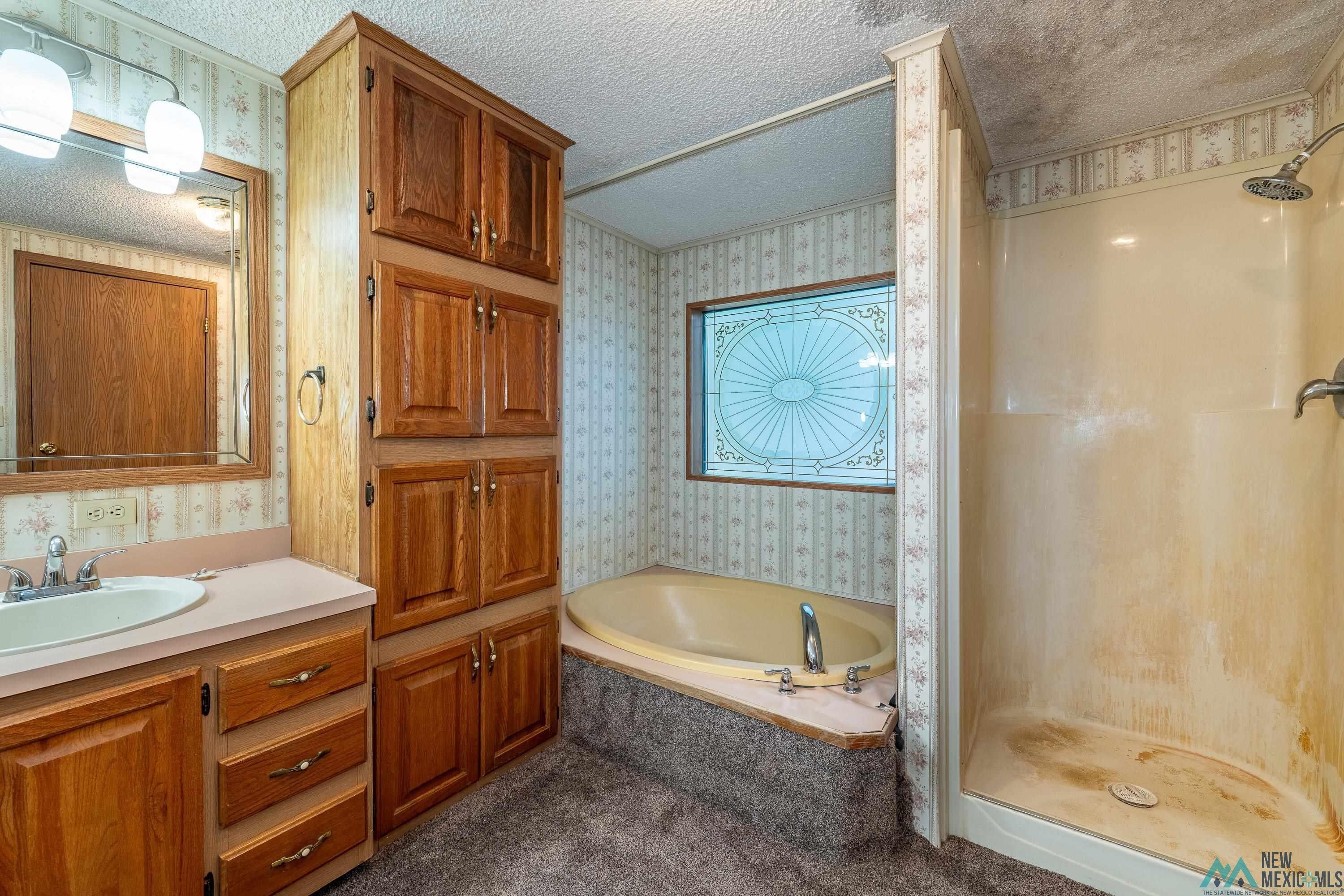 35234 Highway 87 Raton, NM 87740 - Photo 53 of 90 Bathroom with wallpapered walls, a shower stall, a bath, a textured ceiling, and vanity