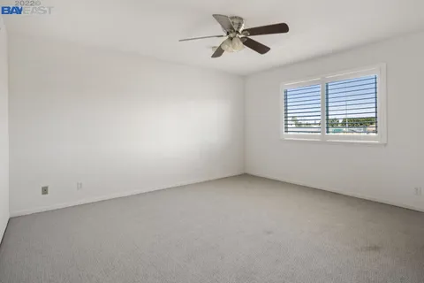 an empty room with a window and a ceiling fan