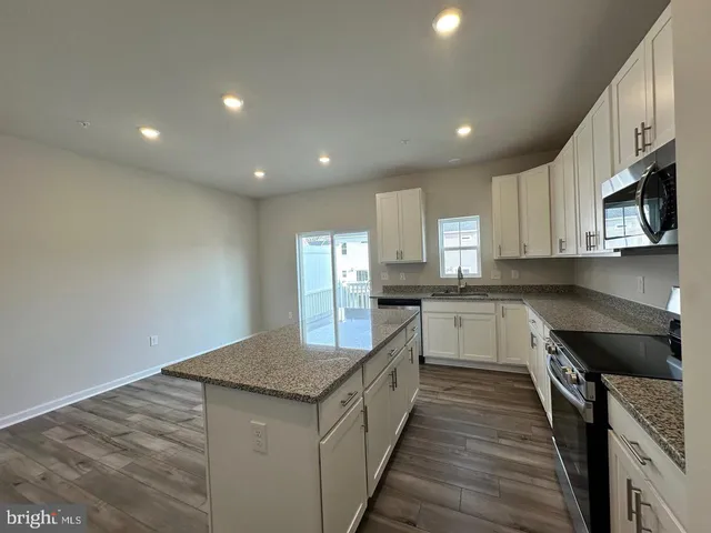 a kitchen with granite countertop white cabinets and stainless steel appliances