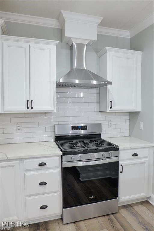 32028 Chestnut Ridge Road North Ridgeville, OH 44039 - Photo 17 of 39 Kitchen with white cabinetry, gas range, light stone counters, decorative backsplash, and wall chimney exhaust hood