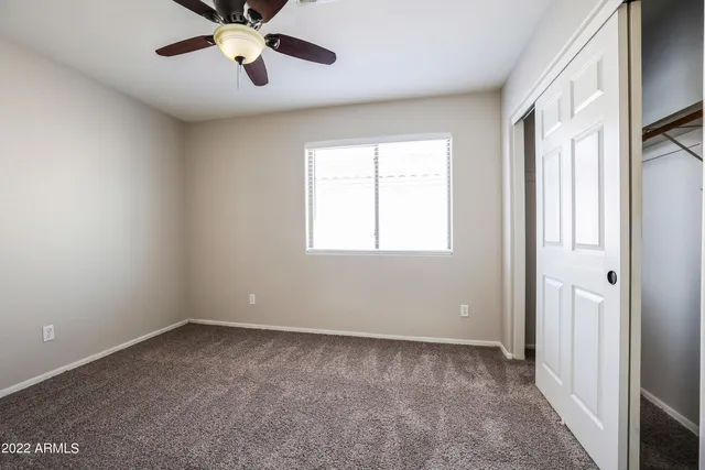 an empty room with windows and fan