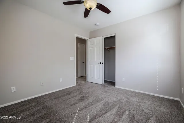 an empty room with a ceiling fan and window