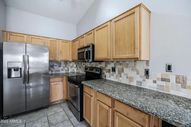 a kitchen with stainless steel appliances granite countertop a refrigerator a stove and a sink with granite countertops