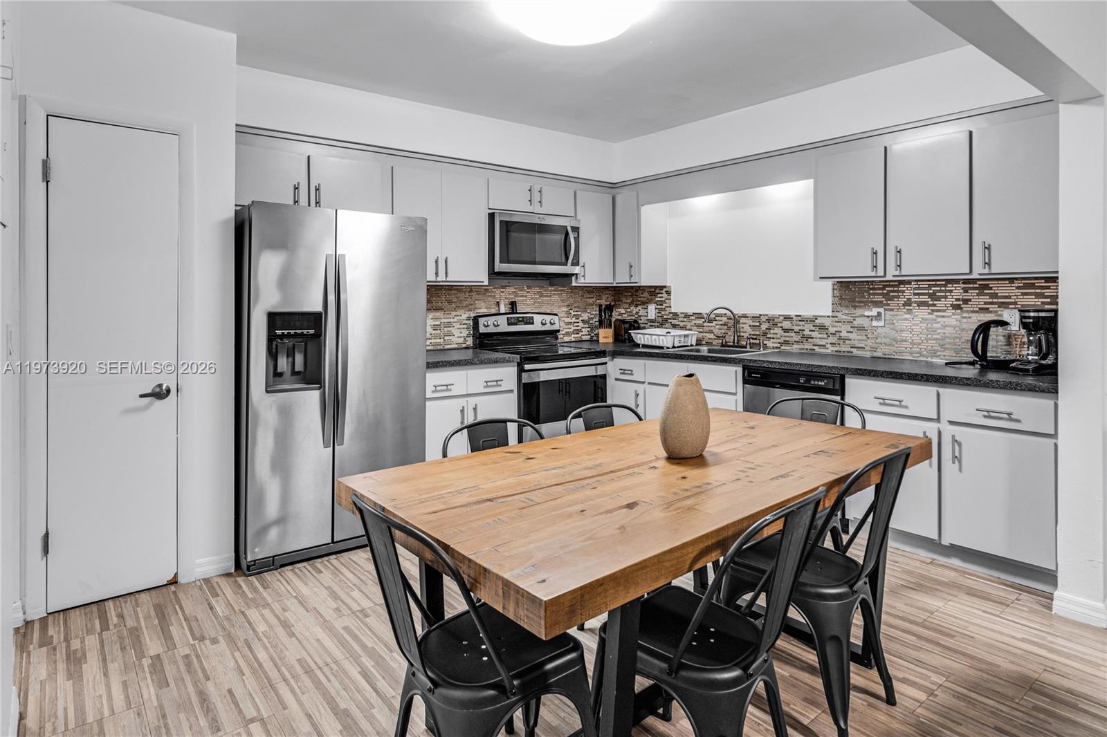977 Southwest 10th Street, Unit 927 Miami, FL 33130 - Photo 4 of 18 a kitchen with stainless steel appliances granite countertop a dining table chairs refrigerator and microwave