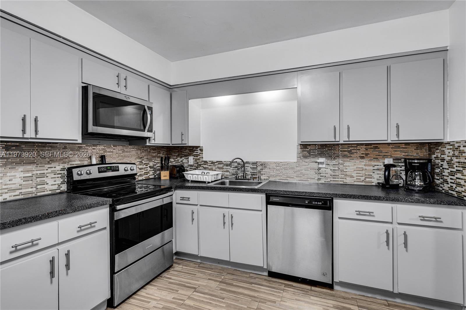977 Southwest 10th Street, Unit 927 Miami, FL 33130 - Photo 6 of 18 a kitchen with granite countertop white cabinets and stainless steel appliances
