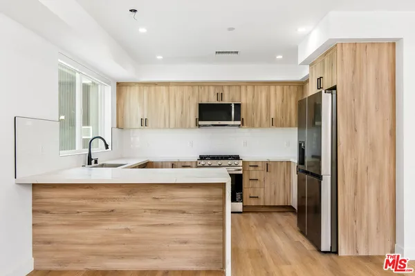 a kitchen with stainless steel appliances granite countertop a refrigerator and a stove top oven