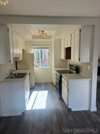 a kitchen with granite countertop a stove a sink and a refrigerator