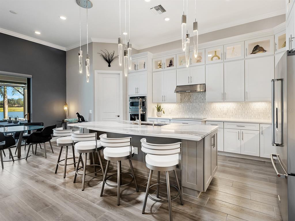 17807 Eastbrook Terrace Lakewood Ranch, FL 34202 - Photo 29 of 92 a kitchen with kitchen island granite countertop a table chairs sink and cabinets